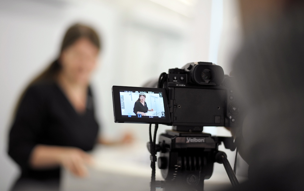 filming a video on professional camera or photoshoot of woman in black in White Hall back photographer blurred background advertising movie production life of ordinary people news incidents interview